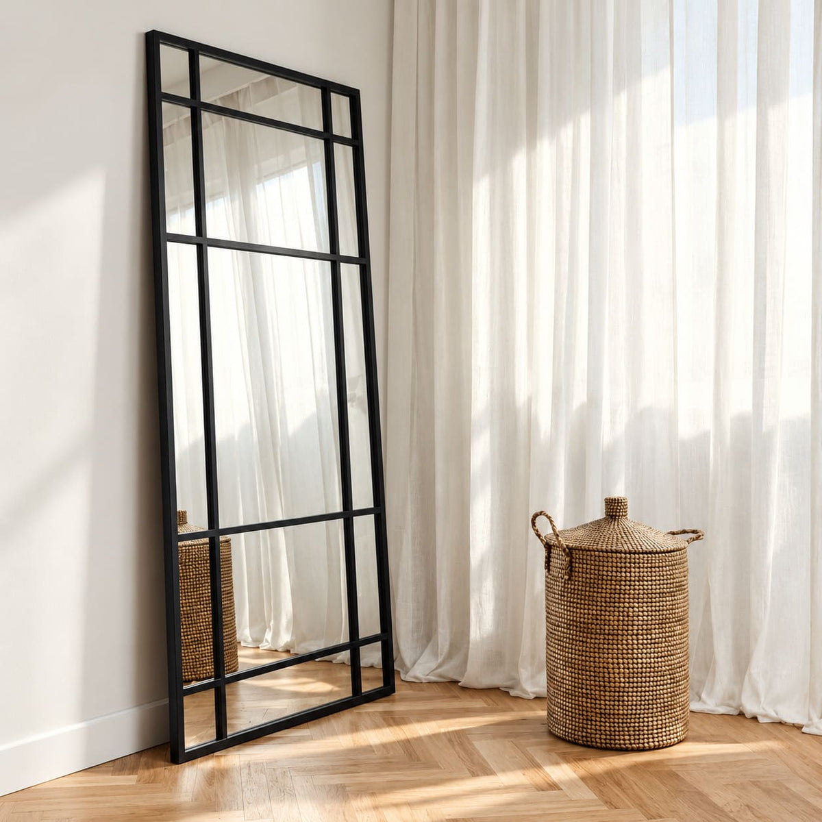 Espejo Ventana XL de cuerpo entero con marco negro y divisiones estilo industrial, apoyado en una pared junto a cortinas blancas.