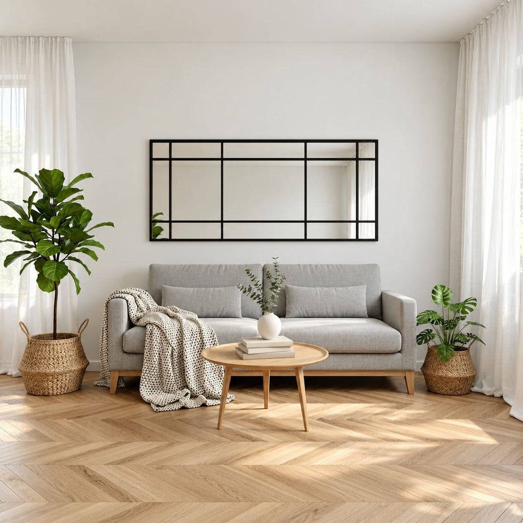 Espejo Ventana XL con marco negro y divisiones estilo industrial, instalado horizontalmente sobre un sofá gris en un living luminoso.