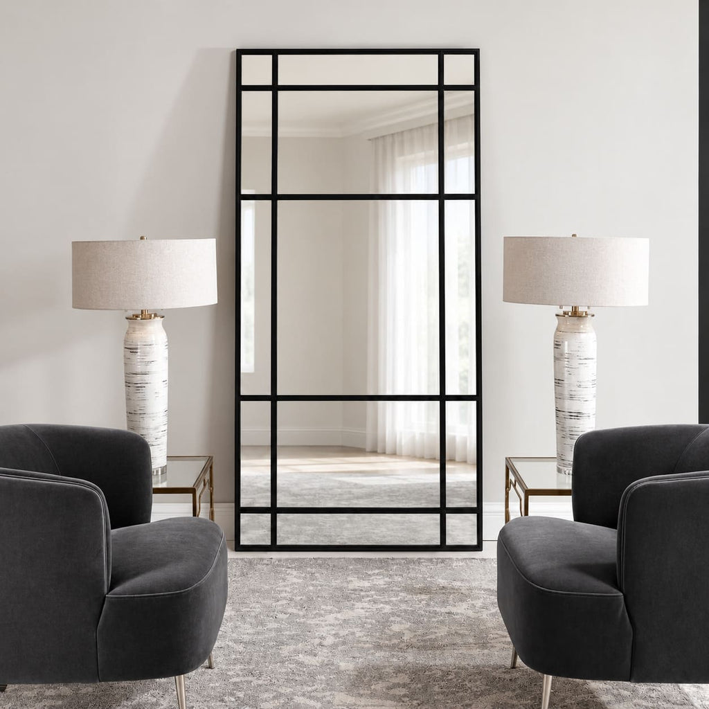 Espejo Ventana XL con marco negro y divisiones estilo industrial, visto de frente entre dos sillones oscuros y lámparas blancas.