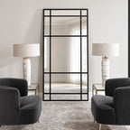 Espejo Ventana XL con marco negro y divisiones estilo industrial, visto de frente entre dos sillones oscuros y lámparas blancas.