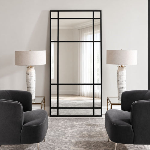 Espejo Ventana XL con marco negro y divisiones estilo industrial, visto de frente entre dos sillones oscuros y lámparas blancas.