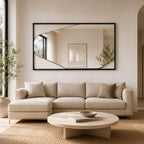 espejo irregular con marco de madera negro colocado encima de un sofa de forma horizontal