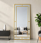 Espejo Glamour de cuerpo entero con marco dorado y divisiones decorativas, colocado verticalmente junto a un mueble.