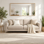 Espejo horizontal con marco de pino natural sobre un sofá beige, rodeado de plantas en un living luminoso.