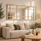 Espejo ventana de madera natural sobre sofá en living, espejo decorativo grande de estilo cálido y moderno.