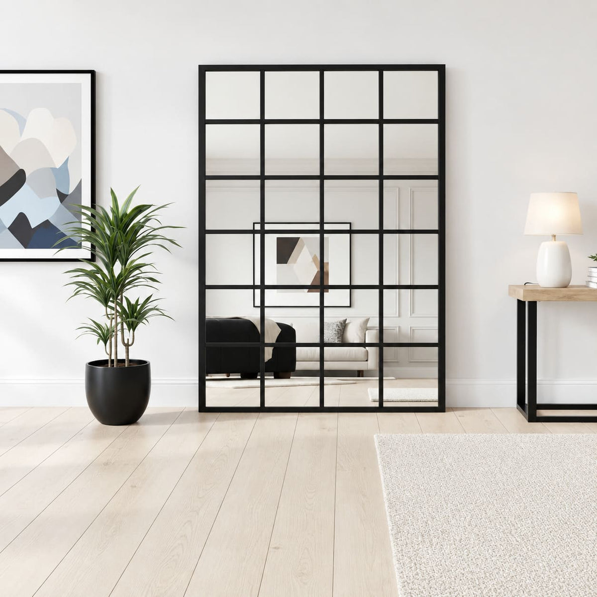 Espejo grande estilo ventana con marco negro y divisiones cuadriculadas, apoyado en el suelo junto a una planta.